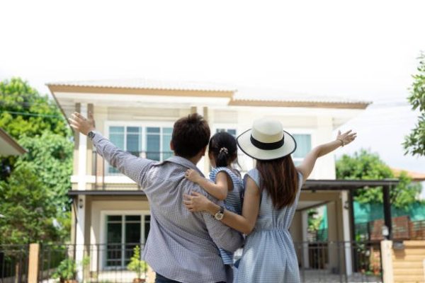 Happy Asian family. Father, mother and daughter near new home. Real estate background with copy space